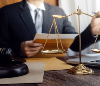 Justice and law concept.Male judge in a courtroom with the gavel, working with, computer and docking keyboard, eyeglasses, on table in morning light