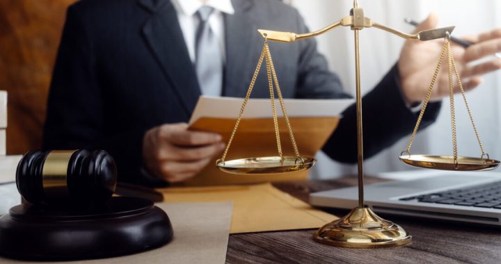 Justice and law concept.Male judge in a courtroom with the gavel, working with, computer and docking keyboard, eyeglasses, on table in morning light